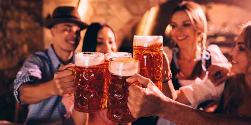 Junge Menschen in Tracht, die sich mit Bier zuprosten